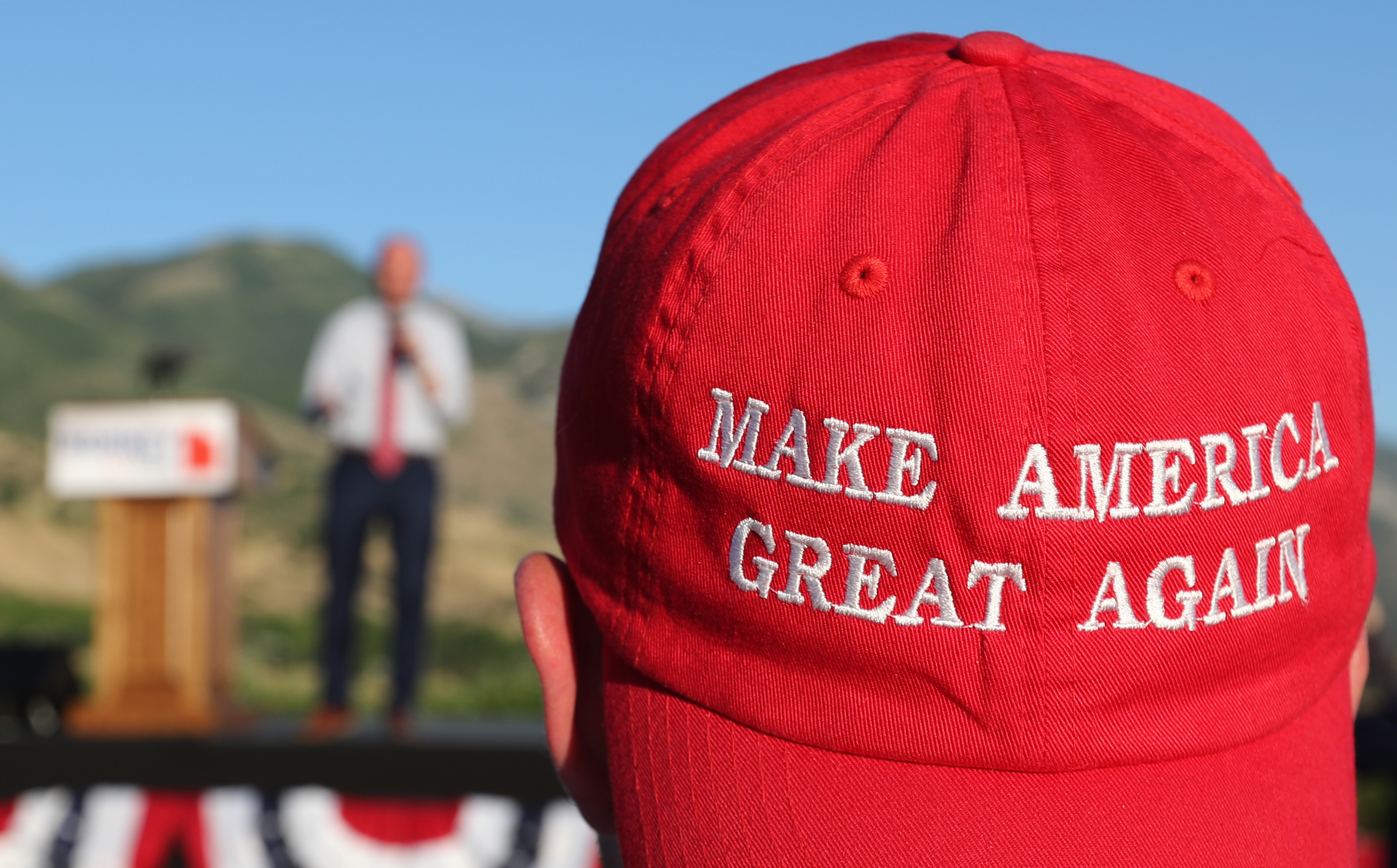 A Romney supporter listens to a speaker as he wears a "Make America Great Again" hat at the Mitt Romney election party on June 26, 2018 in Orem, Utah. (Photo by George Frey/Getty Images)