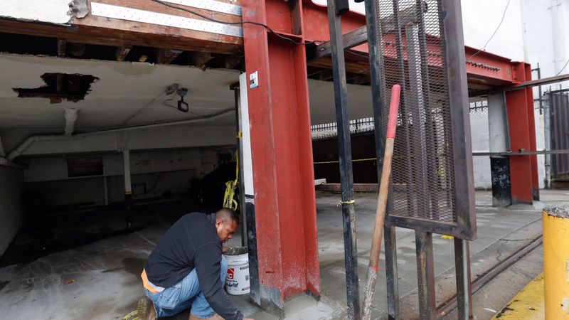 Kehl Tonga, a supervisor for Cal-Quake Construction, adds cement to the base of a steel moment frame, installed to retrofit the flimsy first story of an apartment building in Hollywood in this undated photo. (Credit: Mel Melcon / Los Angeles Times)