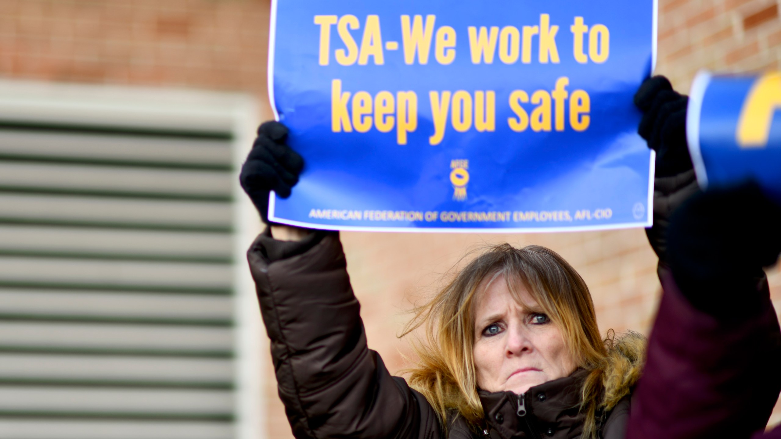 Elizabeth Hughes holds a placard stating "TSA- We work to keep you safe" while demonstrating with Philadelphia Airport TSA and airport workers outside the Philadelphia International Airport on January 25, 2019 in Philadelphia, Pennsylvania. (Credit: Mark Makela/Getty Images)