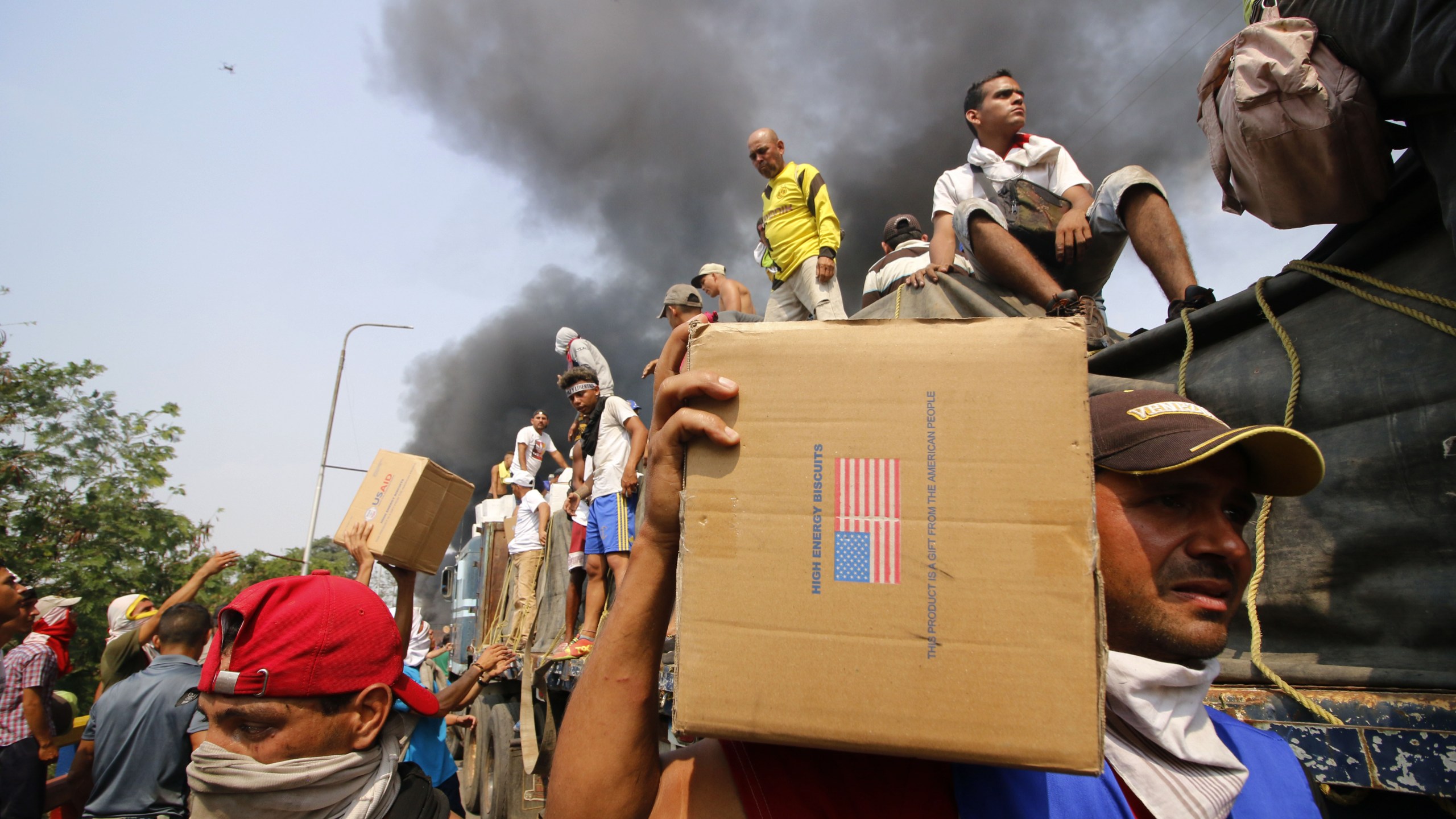 People try to salvage humaitarian aid after the truck carrying it was set ablaze on the Francisco de Paula Santander International Brige between Cucuta in Colombia and Ureña in Venezuela, on Feb. 23, 2019. (Credit: SCHNEYDER MENDOZA/AFP/Getty Images)