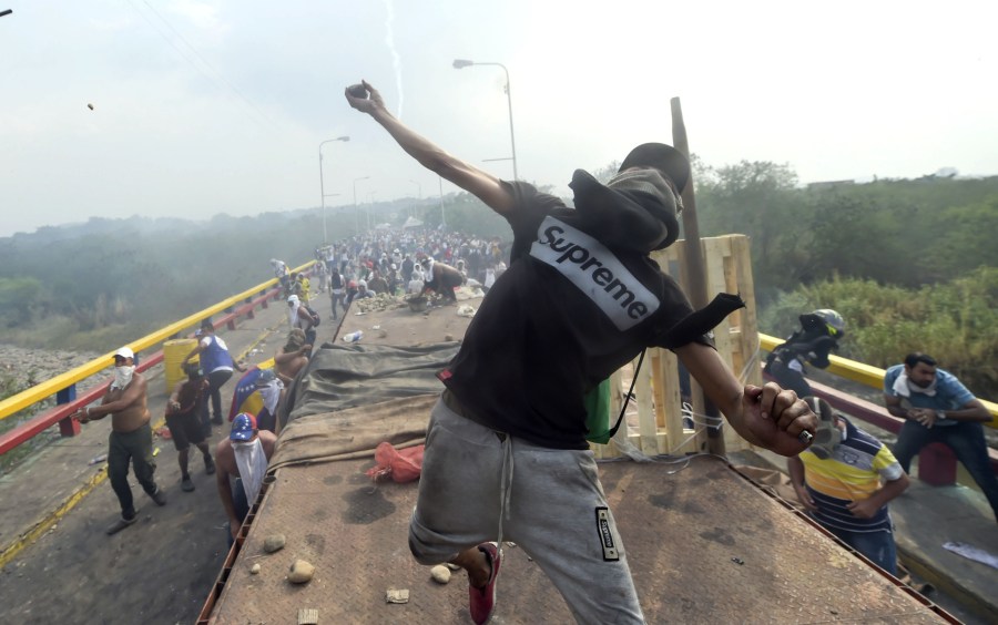 Demonstrators throw stones in clashes with the security forces at the Francisco de Paula Santander international bridge Bridge linking Cucuta, Colombia, and Urena, Venezuela, during an attempt to cross humanitarian aid over the border into Venezuela, on Feb. 23, 2019. (Credit: RAUL ARBOLEDA/AFP/Getty Images)