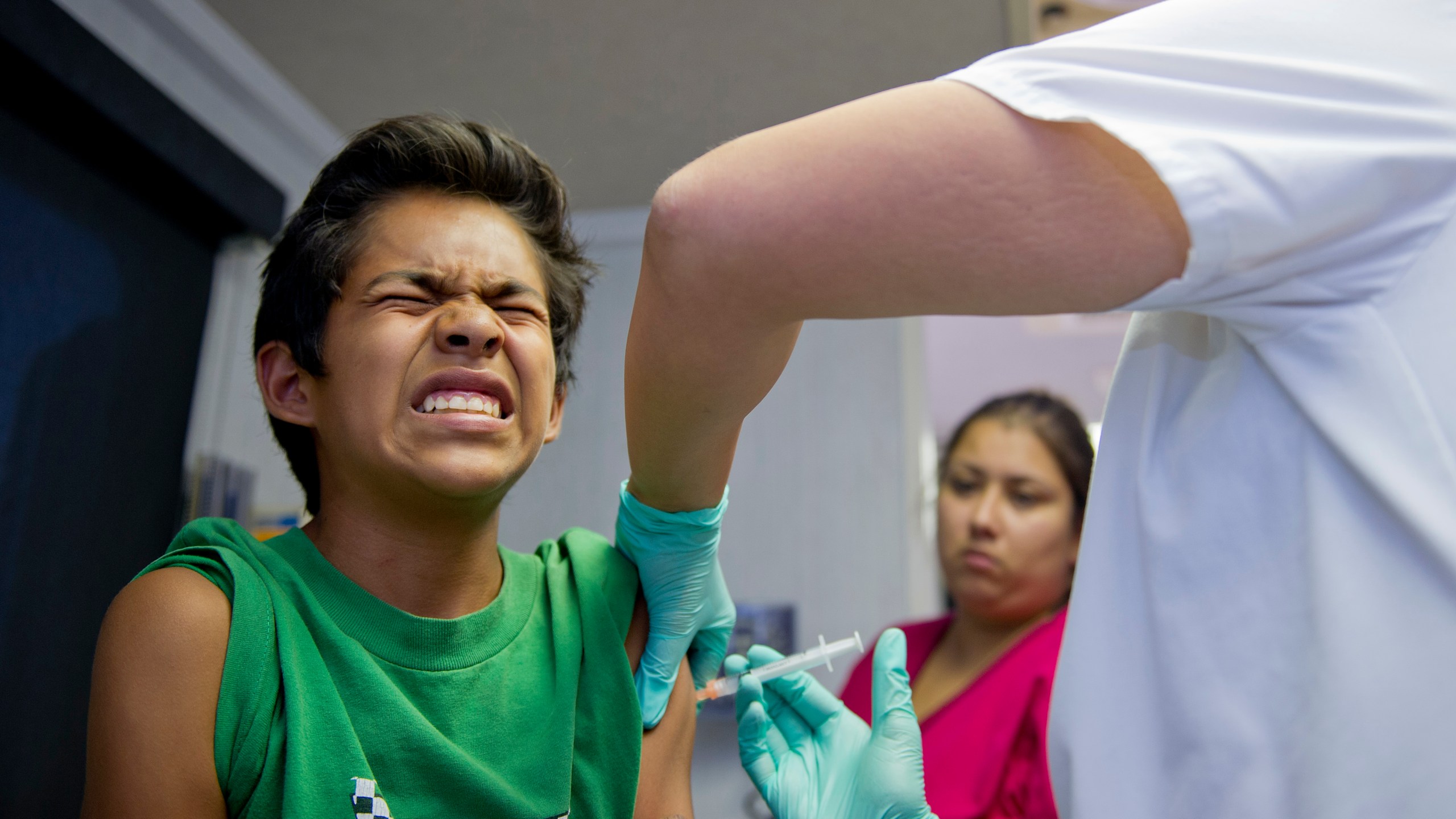 A public school student grimaces as he gets a vaccination at a free immunization clinic for students before the start of the school year in Lynwood on Aug. 27, 2013. (Credit: Robyn Beck/AFP/Getty Images)