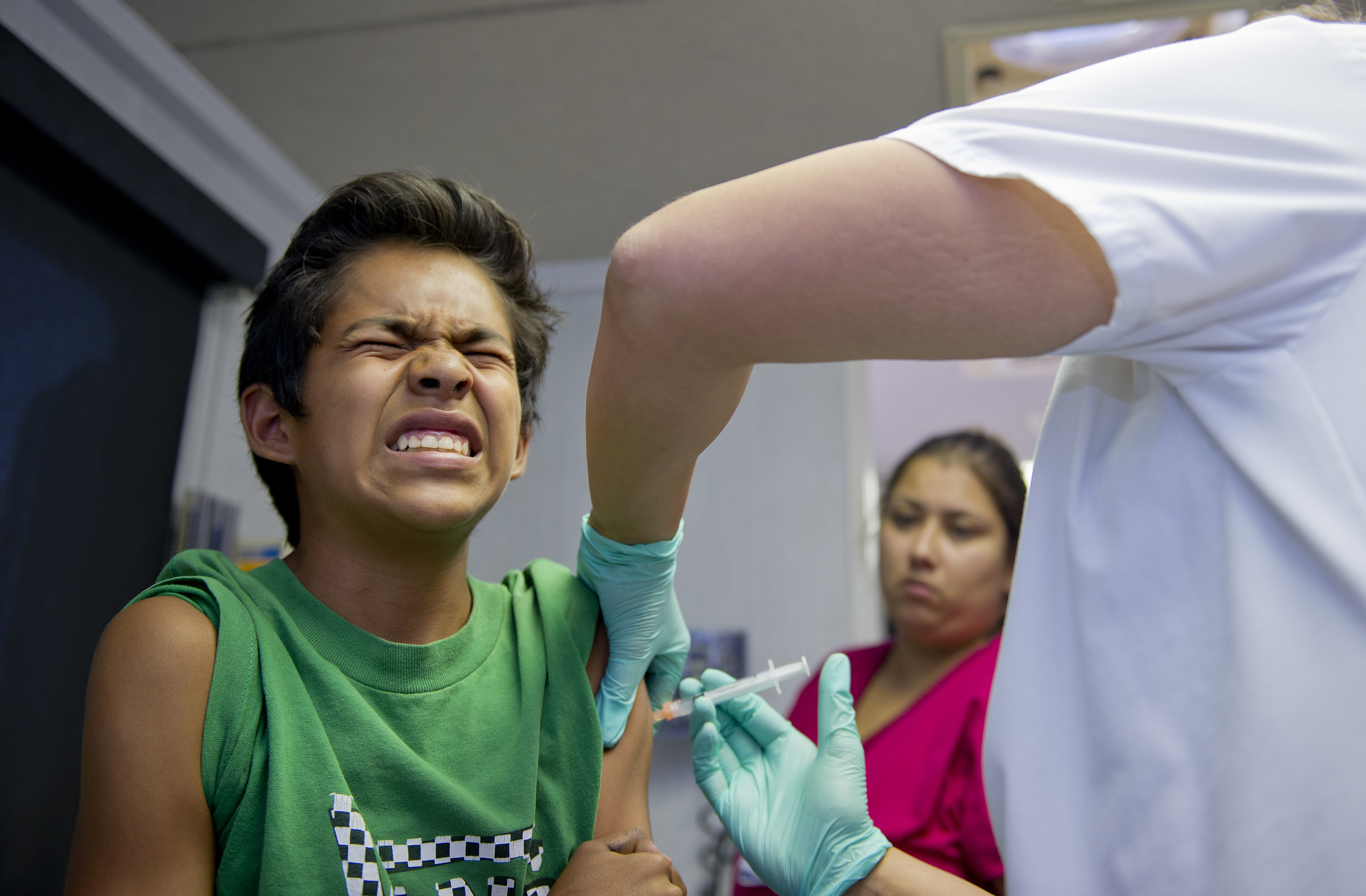 A public school student grimaces as he gets a vaccination at a free immunization clinic for students before the start of the school year in Lynwood on Aug. 27, 2013. (Credit: Robyn Beck/AFP/Getty Images)