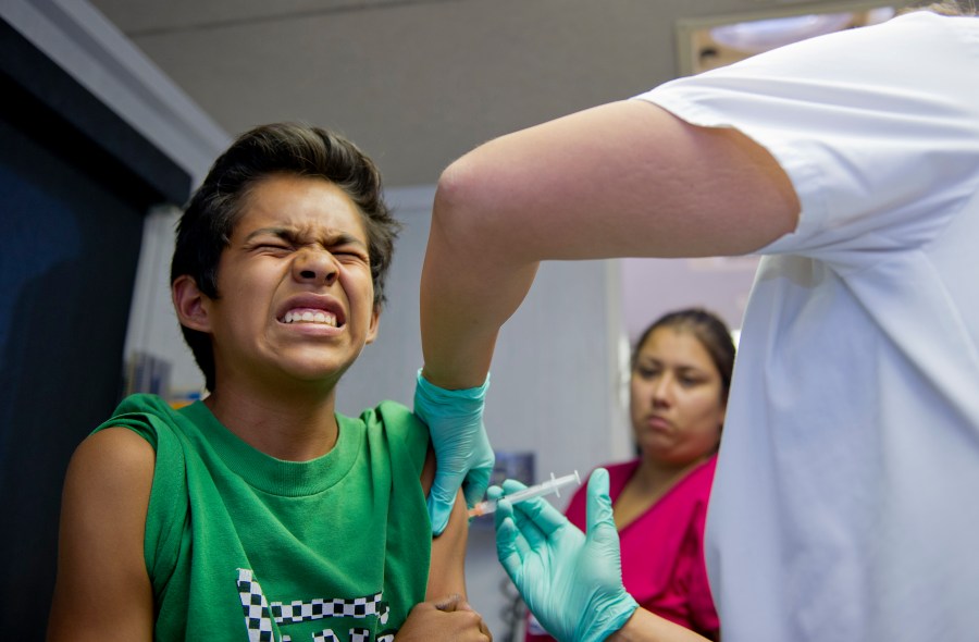 A public school student grimaces as he gets a vaccination at a free immunization clinic for students before the start of the school year in Lynwood on Aug. 27, 2013. (Credit: Robyn Beck/AFP/Getty Images)