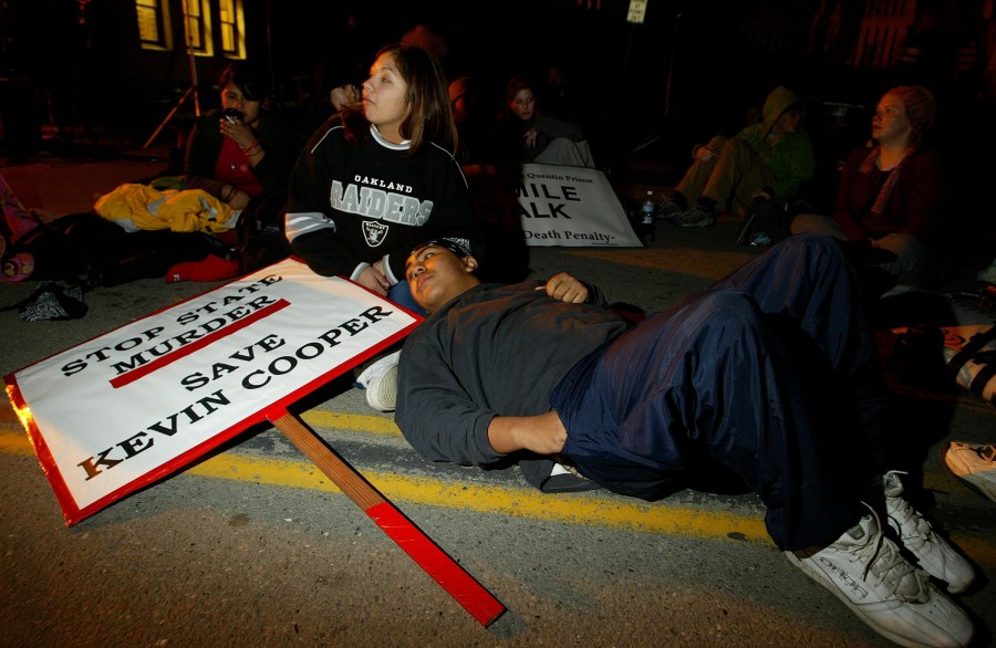 Muranda Jacques and Leo Lopez of San Jose rest outside of California State Prison at San Quentin on Feb. 9, 2004, as they protested in opposition to the execution of convicted killer Kevin Cooper. (Credit: Justin Sullivan/Getty Images)