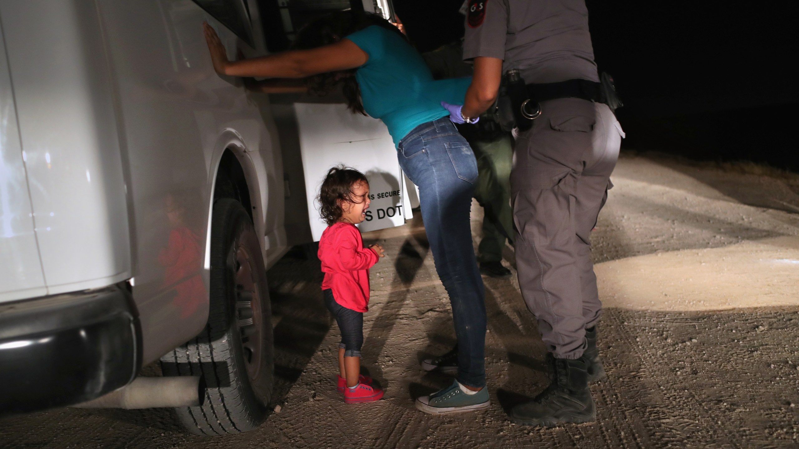 A two-year-old Honduran asylum seeker cries as her mother is searched and detained near the U.S.-Mexico border on June 12, 2018, in McAllen, Texas. (Credit: John Moore/Getty Images)