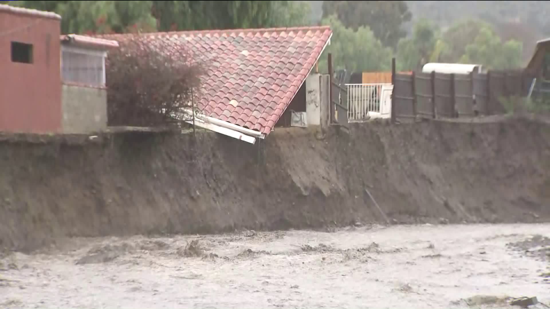 The roof of a structure appears collapsed on an eroded hillside near a rain-swollen creek in Lake Elsinore on Feb. 14, 2019. (Credit: KTLA)