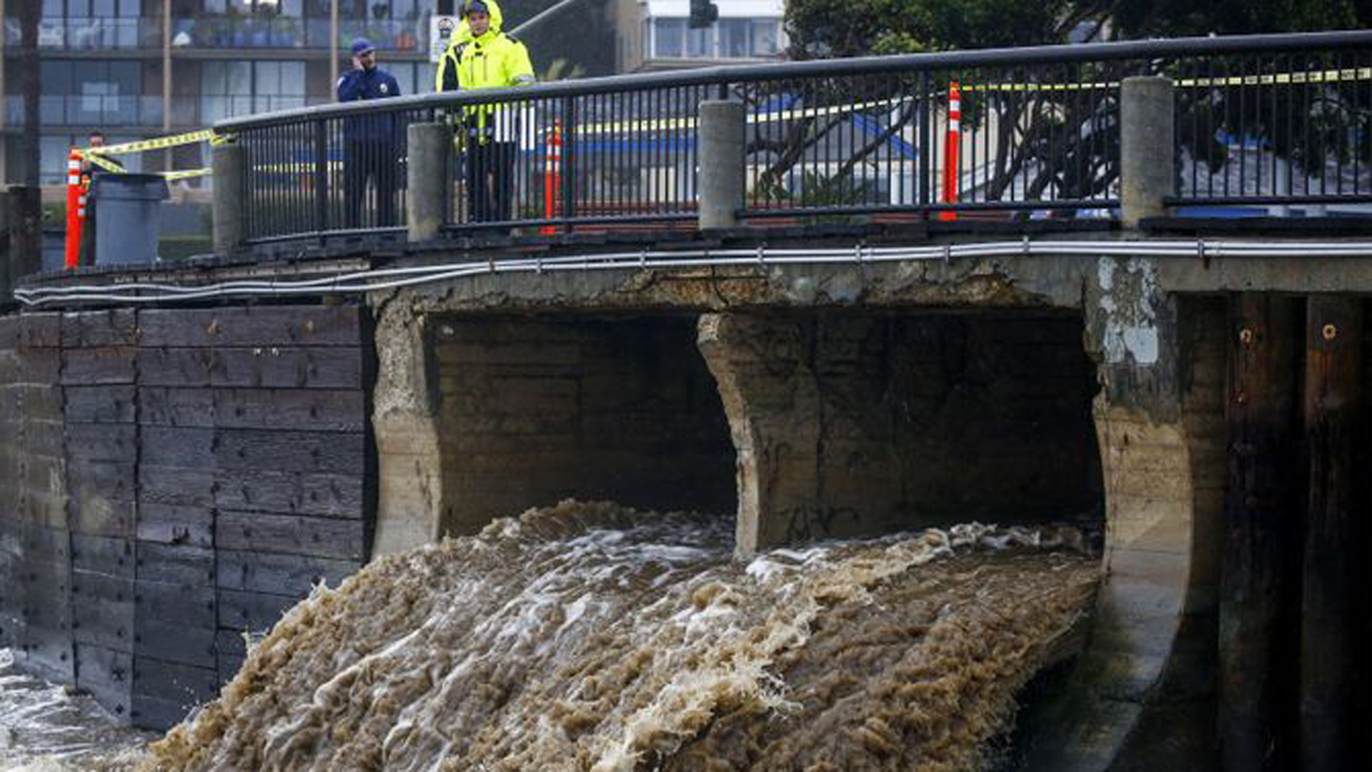 People walking along the Laguna Beach boardwalk look at stormwater pouring out to the ocean in Laguna Beach in an undated photo. (Credit: Kent Nishimura / Los Angeles Times)