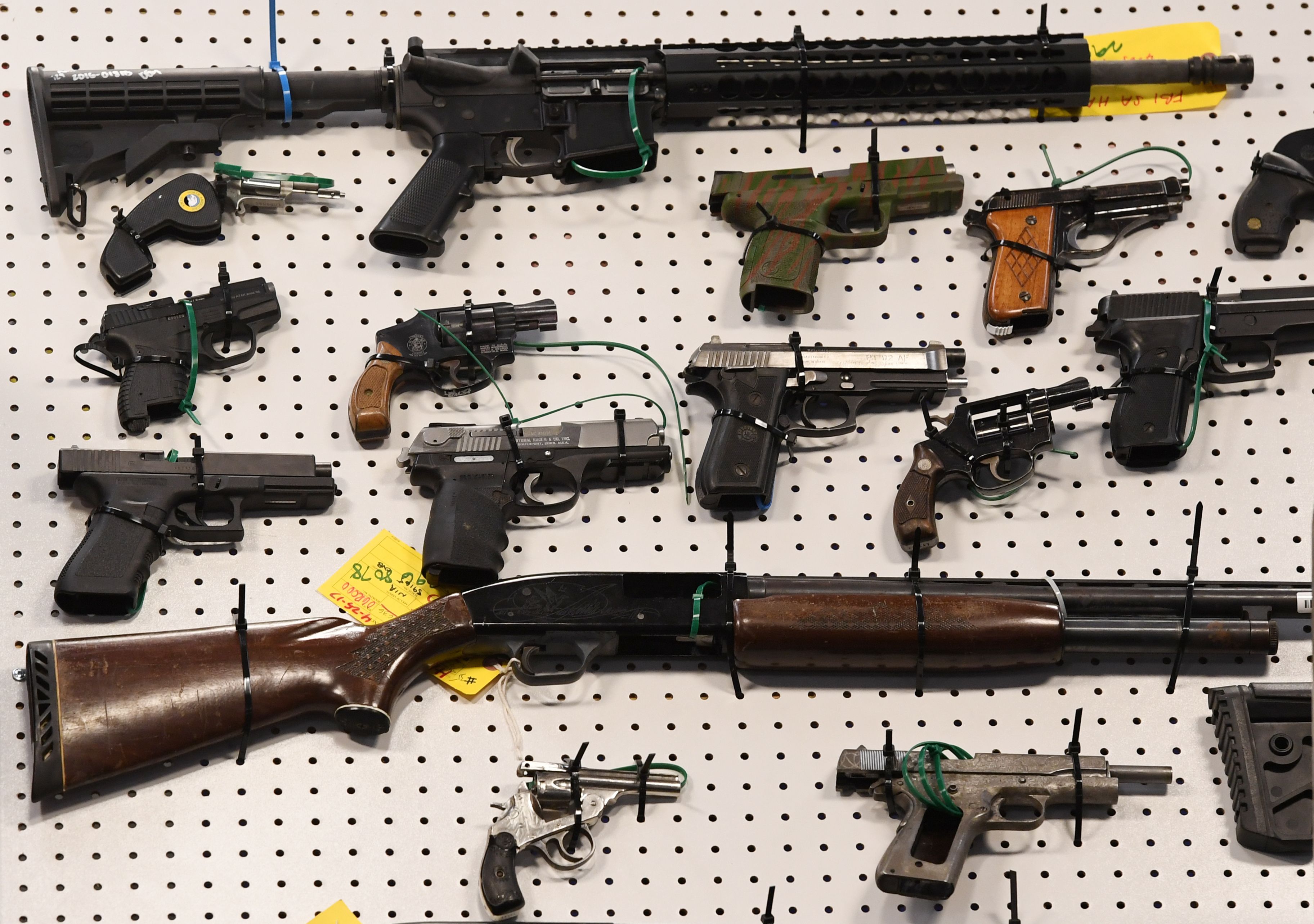 Representatives from the FBI and Los Angeles Police Department display weapons seized after a raid in which three dozen reputed members of street gangs from the San Fernando Valley and South Los Angeles were arrested on Feb. 13, 2019. (Mark Ralston / AFP / Getty Images)