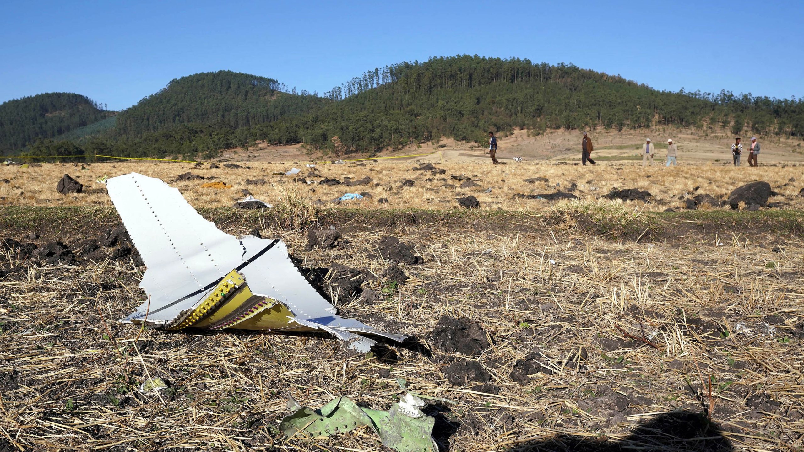 A piece of the fuselage of ET Flight 302 can be seen in the foreground as local residents collect debris at the scene where Ethiopian Airlines Flight 302 crashed in a wheat field on March 10, 2019, in Addis Ababa, Ethiopia. (Credit: Jemal Countess/Getty Images)