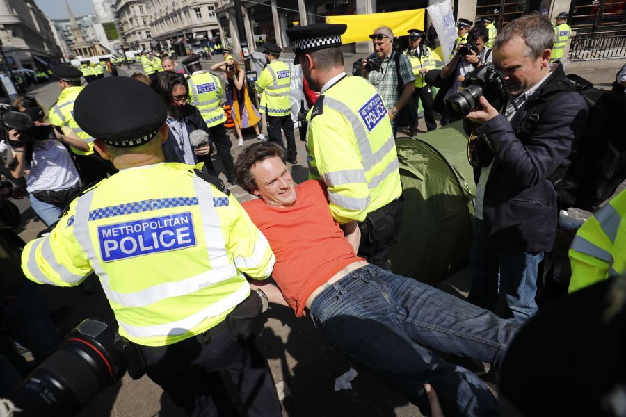 Police officers carry away a climate change activist who was occupying the road junction at Oxford Circus in central London on April 19, 2019. (Credit: TOLGA AKMEN/AFP/Getty Images)