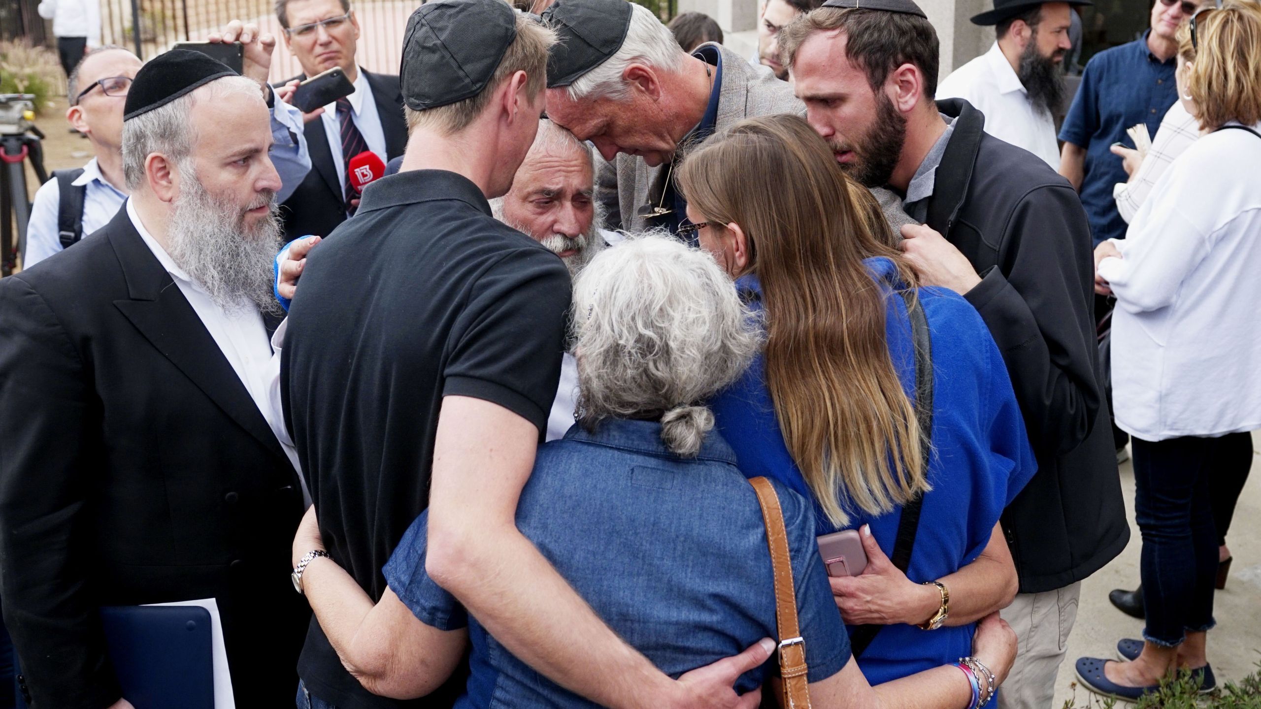 Executive Director Rabbi Yisroel Goldstein (center), who was shot in the hands, hugs his congregants after a press conference outside the Chabad of Poway Synagogue on April 28, 2019. (Credit: SANDY HUFFAKER/AFP/Getty Images)