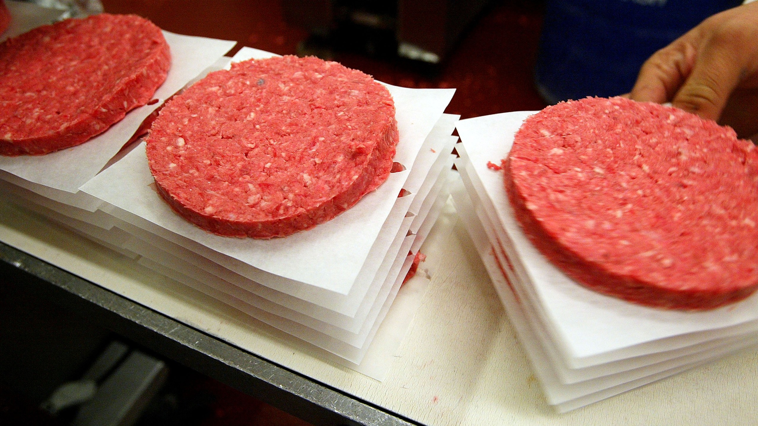 Eliseo Araujo removes ground beef patties from a conveyor belt at Ray's Wholesale Meats December 29, 2003, in Yakima, Washington. (Credit: Justin Sullivan/Getty Images)