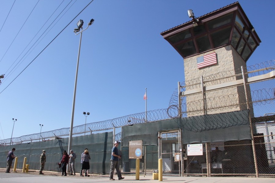 People walk past a guard tower outside the fencing of Camp 5 at the U.S. Military's Prison in Guantanamo Bay, Cuba on Jan. 26, 2017.(Credit: THOMAS WATKINS/AFP/Getty Images)