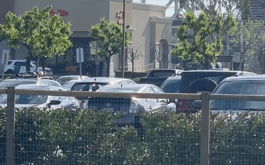 Police officers stand by a building during a shootout in Manhattan Beach on April 7, 2019. (Credit: Kevin McCullough)