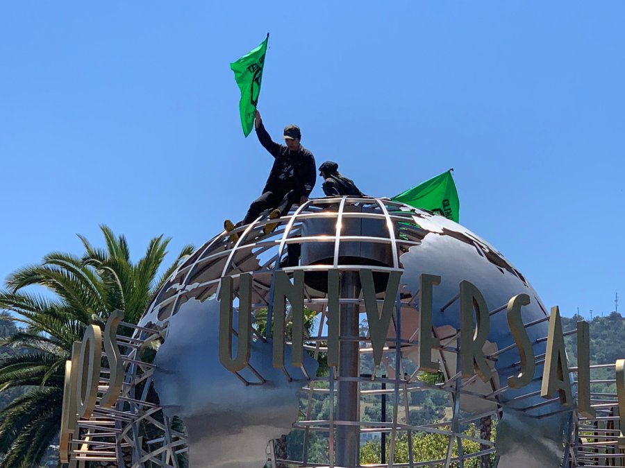 Two protesters sit atop the globe at Universal Studios Hollywood on April 22, 2019. (Credit: @Secretkat3 via Twitter)