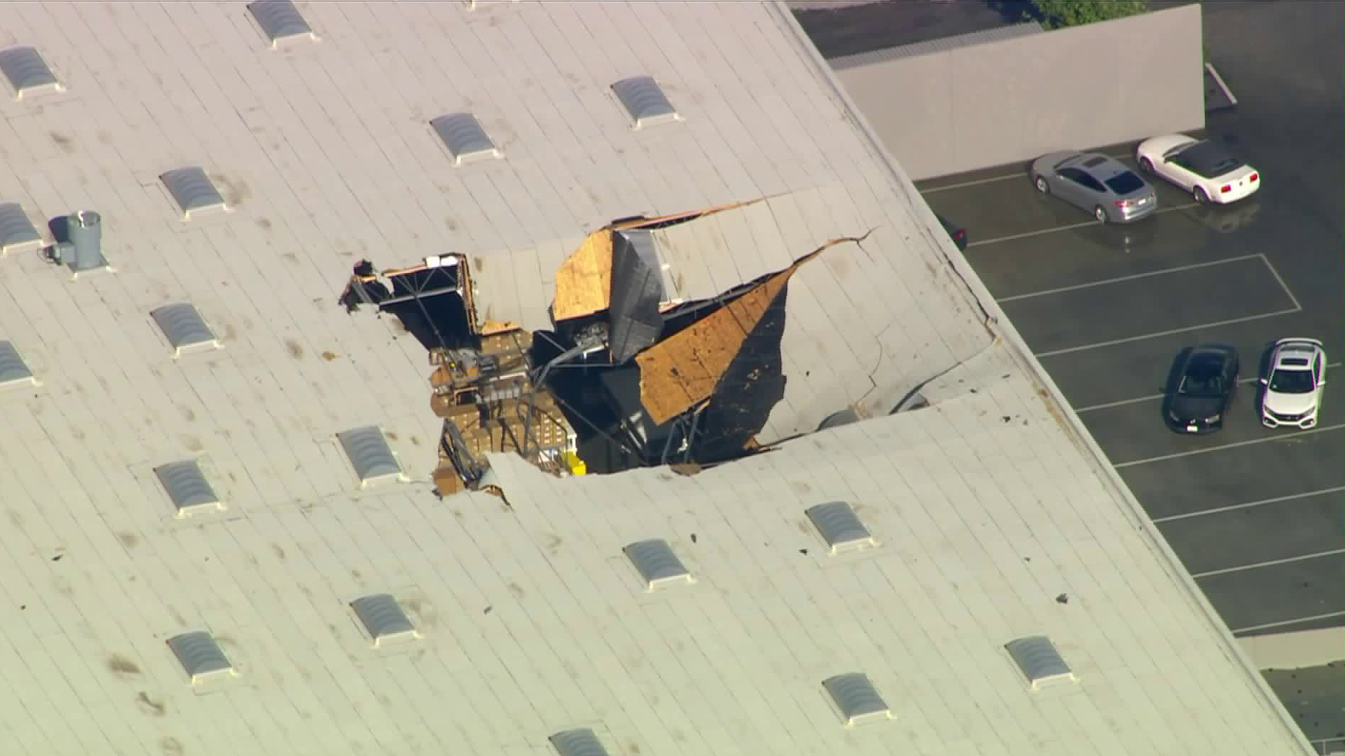 A large hole is visible in the roof of a building after an F-16 pilot ejected just before the aircraft crashed near March Air Reserve Base in Riverside County on May 16, 2019. (Credit: KTLA)