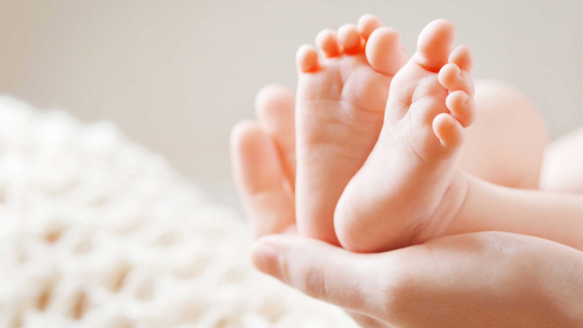 A mother holds a newborn baby's feet in this file photo. (Credit: iStock / Getty Images Plus)