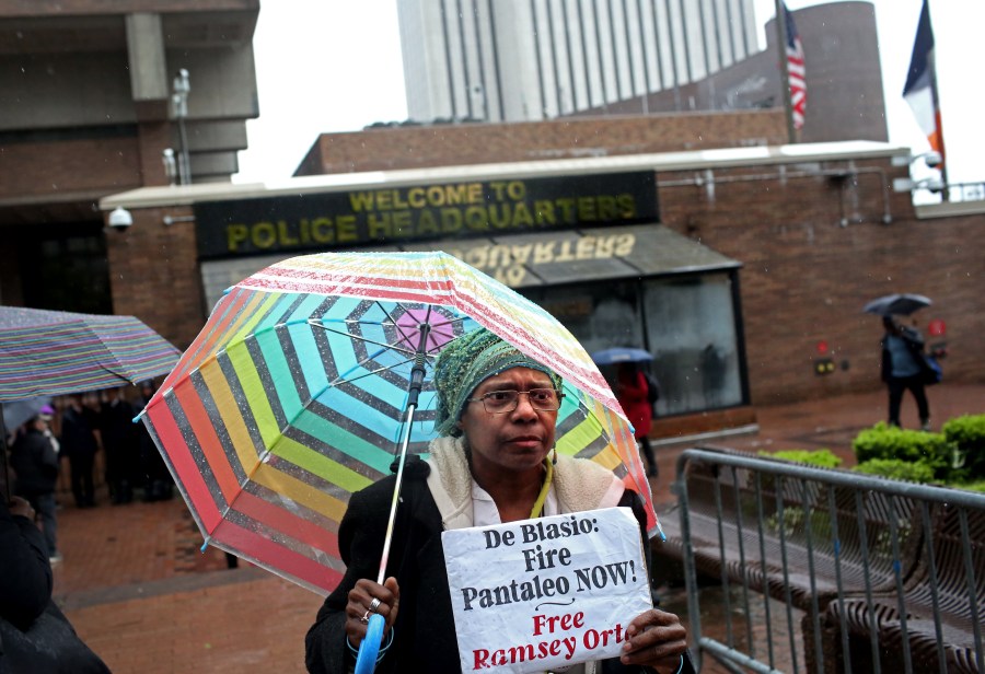 An activist who goes by the name Sista Shirley, 62, from Staten Island, holds up a sign as a line of people awaits entry to the trial of Officer Daniel Pantaleo at One Police Plaza on May 13, 2019 in New York City. (Credit: Yana Paskova/Getty Images)