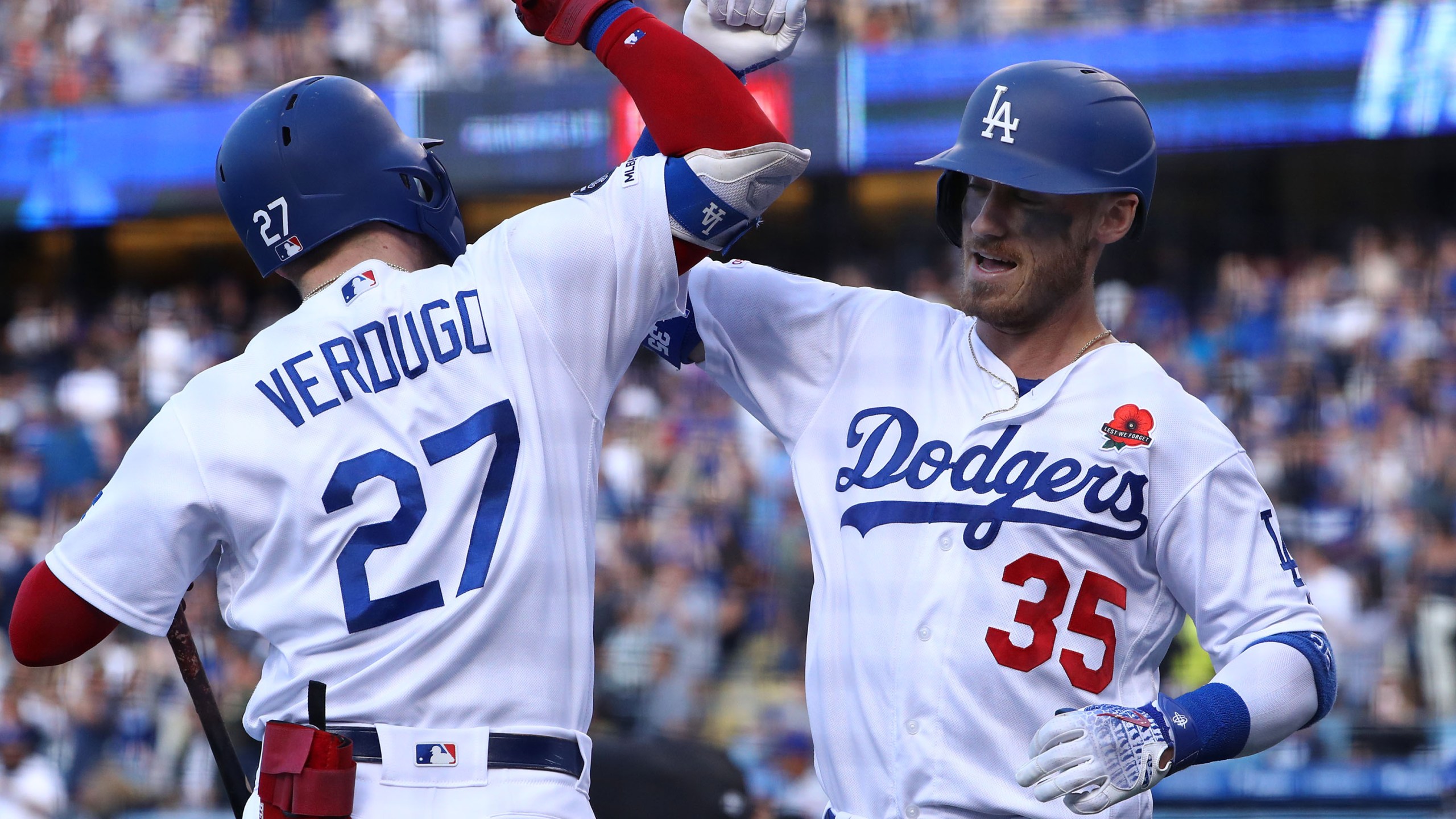 Cody Bellinger, No. 35 of the Los Angeles Dodgers, celebrates with teammate Alex Verdugo, No. 27, after Bellinger hit a solo home run in the third inning of the game against the New York Mets at Dodger Stadium on May 27, 2019. (Credit: Victor Decolongon / Getty Images)