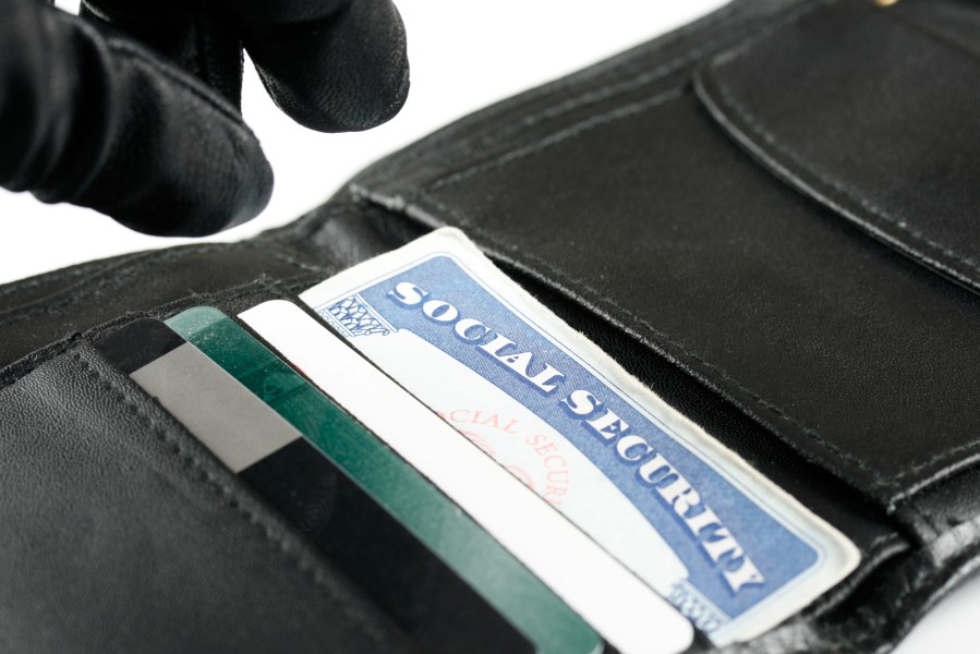 An identity thief's hand is seen reaching for a wallet. (Credit: Getty Images)