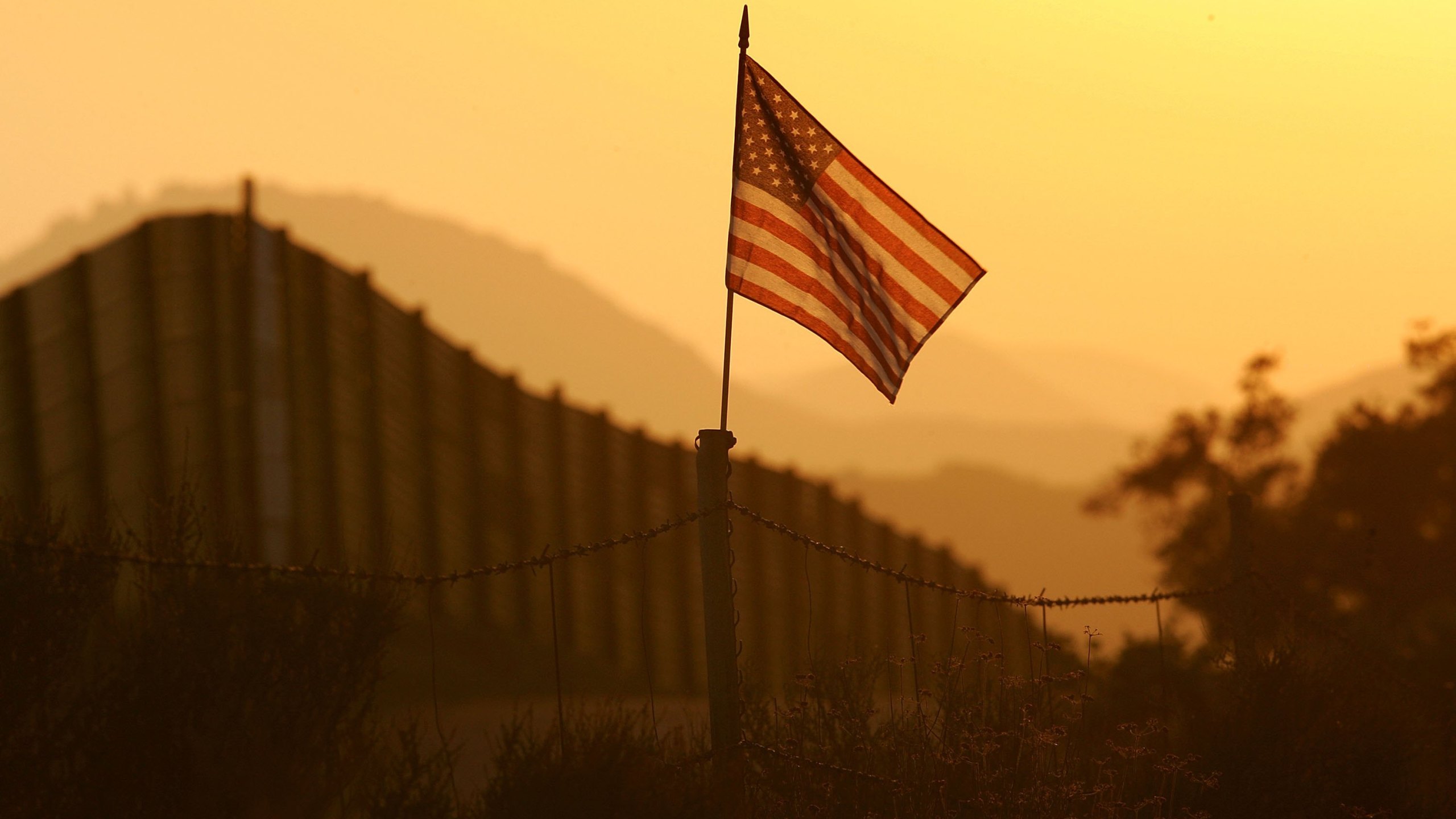 An American flag flies near the US-Mexico border fence in an area where they search for border crossers October 8, 2006 near Campo, California. (Credit: David McNew/Getty Images)