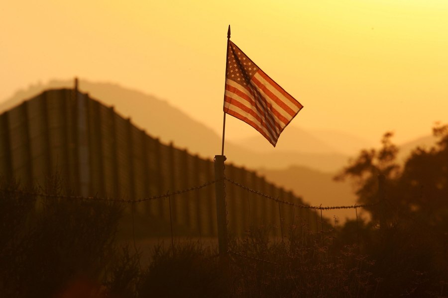 An American flag flies near the US-Mexico border fence in an area where they search for border crossers October 8, 2006 near Campo, California. (Credit: David McNew/Getty Images)