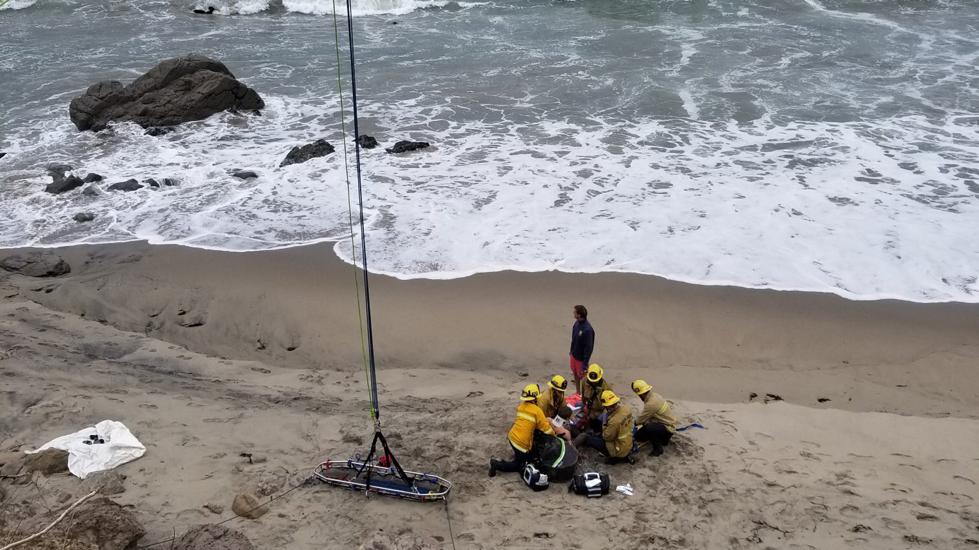 Firefighters treat a man who was injured in a crash landing in a hang glider along Pacific Coast Highway in Ventura County, near the Los Angels County line, on May 26, 2019. (Credit: Ventura County Fire Department)