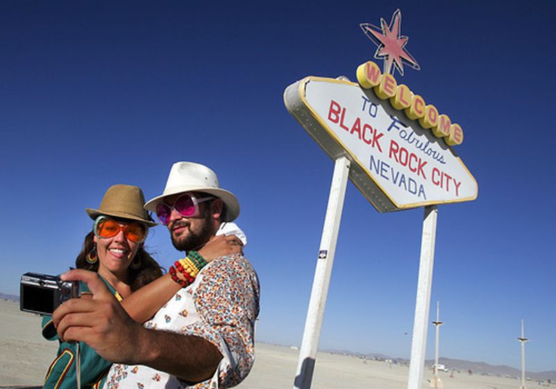 Simone Oliver of San Diego and Eric Weisz of San Francisco take a picture in front of a welcome to Black Rock City sign at Burning Man 2008. (Credit: Spencer Weiner / Los Angeles Times)