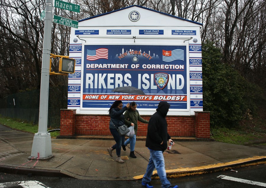 People walk by a sign at the entrance to Rikers Island on March 31, 2017 in New York City. (Credit: Spencer Platt/Getty Images)