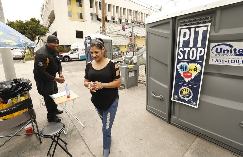 Brenda Chavando thanks Deandre Fradiue who works as the attendant at the portable Pit Stop toilets at Oakwood and Madison Avenues in East Hollywood in June 2019. (Credit: Al Seib / Los Angeles Times)