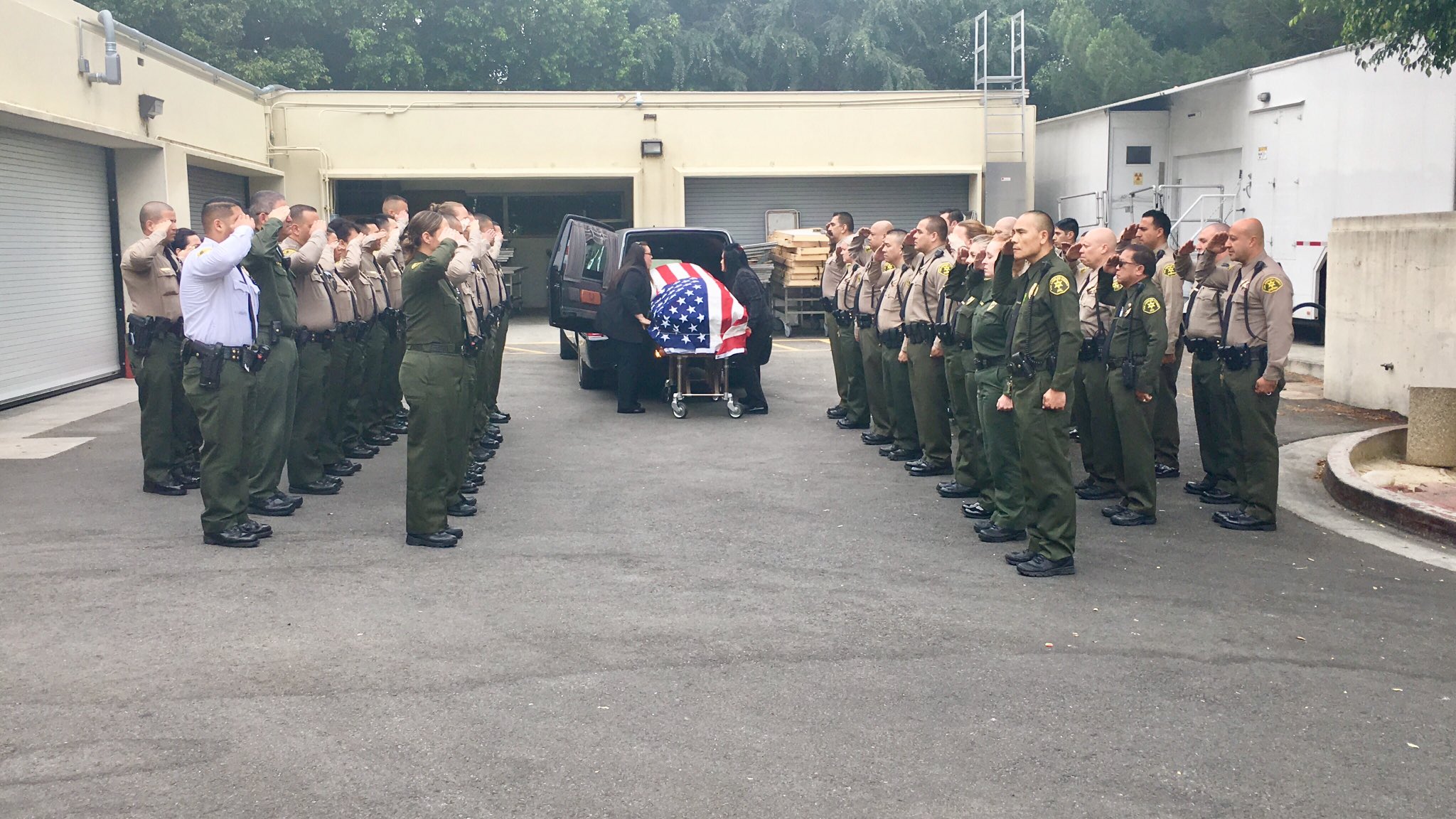 Officers stand behind a hearse ahead of a procession to escort the body of Los Angeles County sheriff's Deputy Joseph Solano from Boyle Heights to East L.A. on June 15, 2019. (Credit: L.A. County Sheriff's Department)