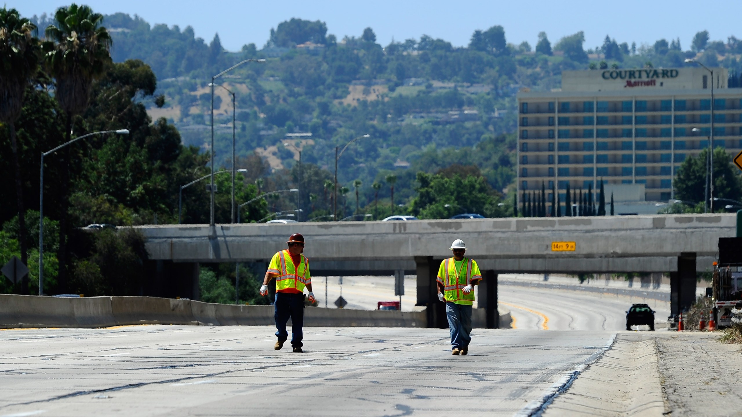 Construction workers walk on the empty southbound lanes of the 405 Freeway as they prepare to re-open a 10-mile stretch of the freeway that was closed for construction on July 17, 2011, in Los Angeles. (Credit: Kevork Djansezian/Getty Images)