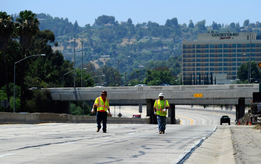 Construction workers walk on the empty southbound lanes of the 405 Freeway as they prepare to re-open a 10-mile stretch of the freeway that was closed for construction on July 17, 2011, in Los Angeles. (Credit: Kevork Djansezian/Getty Images)