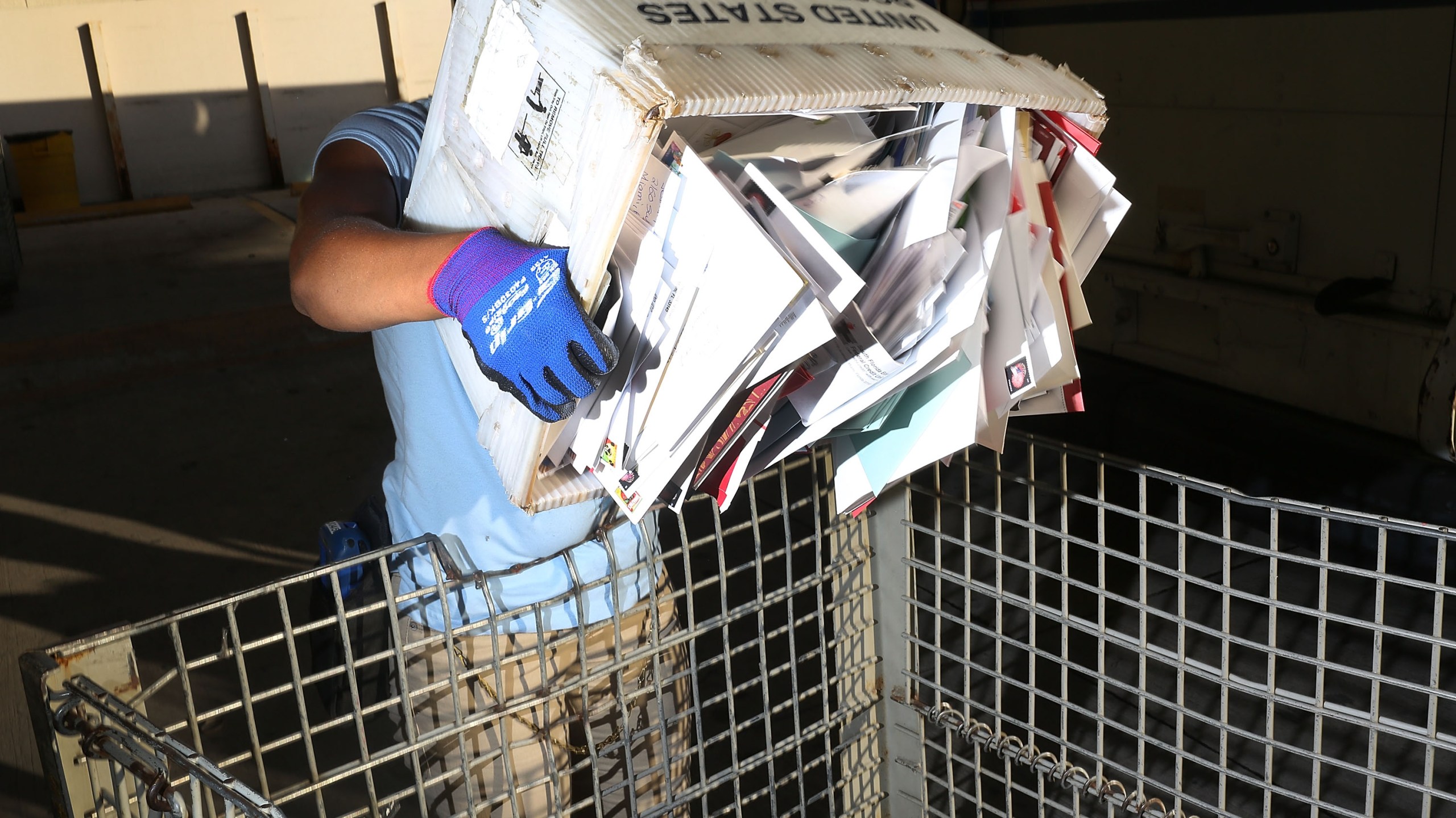 A U.S. Postal Service worker unloads a mail truck at a distribution center in Miami on Dec. 14, 2015. (Credit: Joe Raedle / Getty Images)