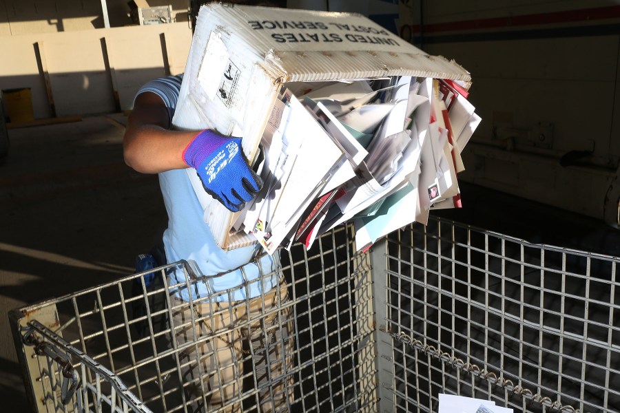 A U.S. Postal Service worker unloads a mail truck at a distribution center in Miami on Dec. 14, 2015. (Credit: Joe Raedle / Getty Images)