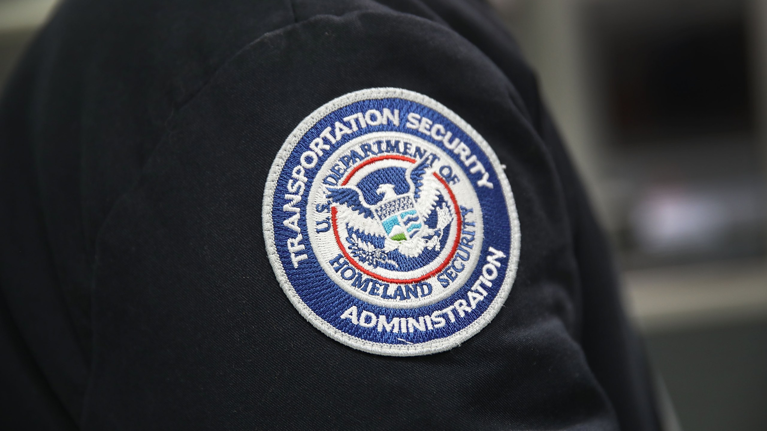 A patch is seen on the jacket of a Transportation Security Administration official as he works at the automated screening lanes funded by American Airlines and installed by the Transportation Security Administration at Miami International Airport on October 24, 2017 in Miami, Florida. (Credit: Joe Raedle/Getty Images)