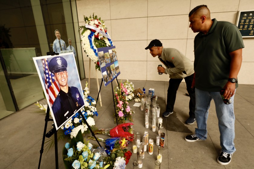 Chris Martin, center, and Ricardo Camacho visit a memorial to slain LAPD officer Juan Jose Diaz in front of LAPD headquarters in July 2019. Camacho’s parents were godparents to Diaz. (Credit: Al Seib / Los Angeles Times)