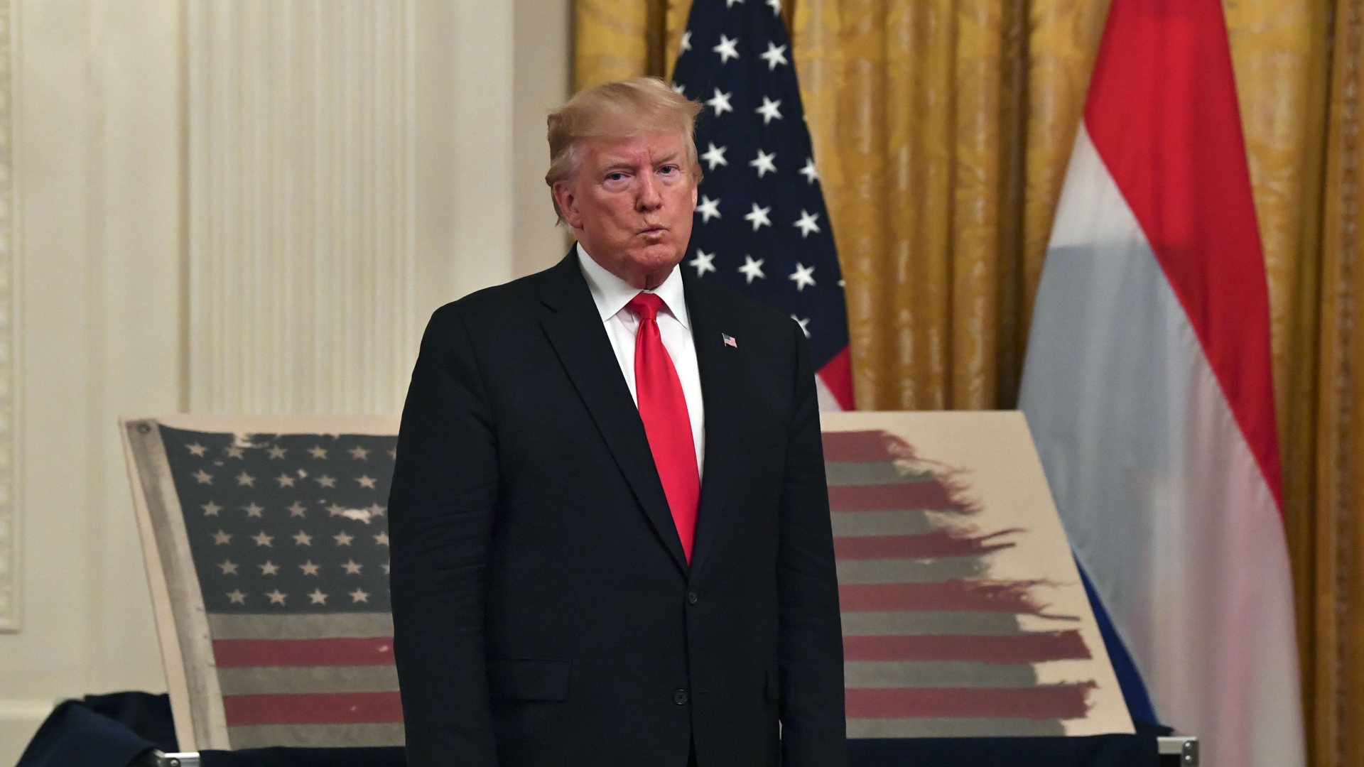 President Donald Trump stands in front of an American flag with Dutch Prime Minister Mark Rutte (not shown) during an East Room ceremony at the White House on July 18, 2019. (Credit: NICHOLAS KAMM/AFP/Getty Images)