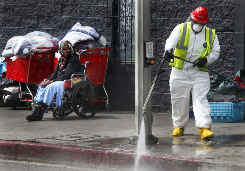 A Los Angeles city sanitation worker sprays the sidewalk during a cleanup on skid row in this undated photo. (Credit: Mark Boster / Los Angeles Times)