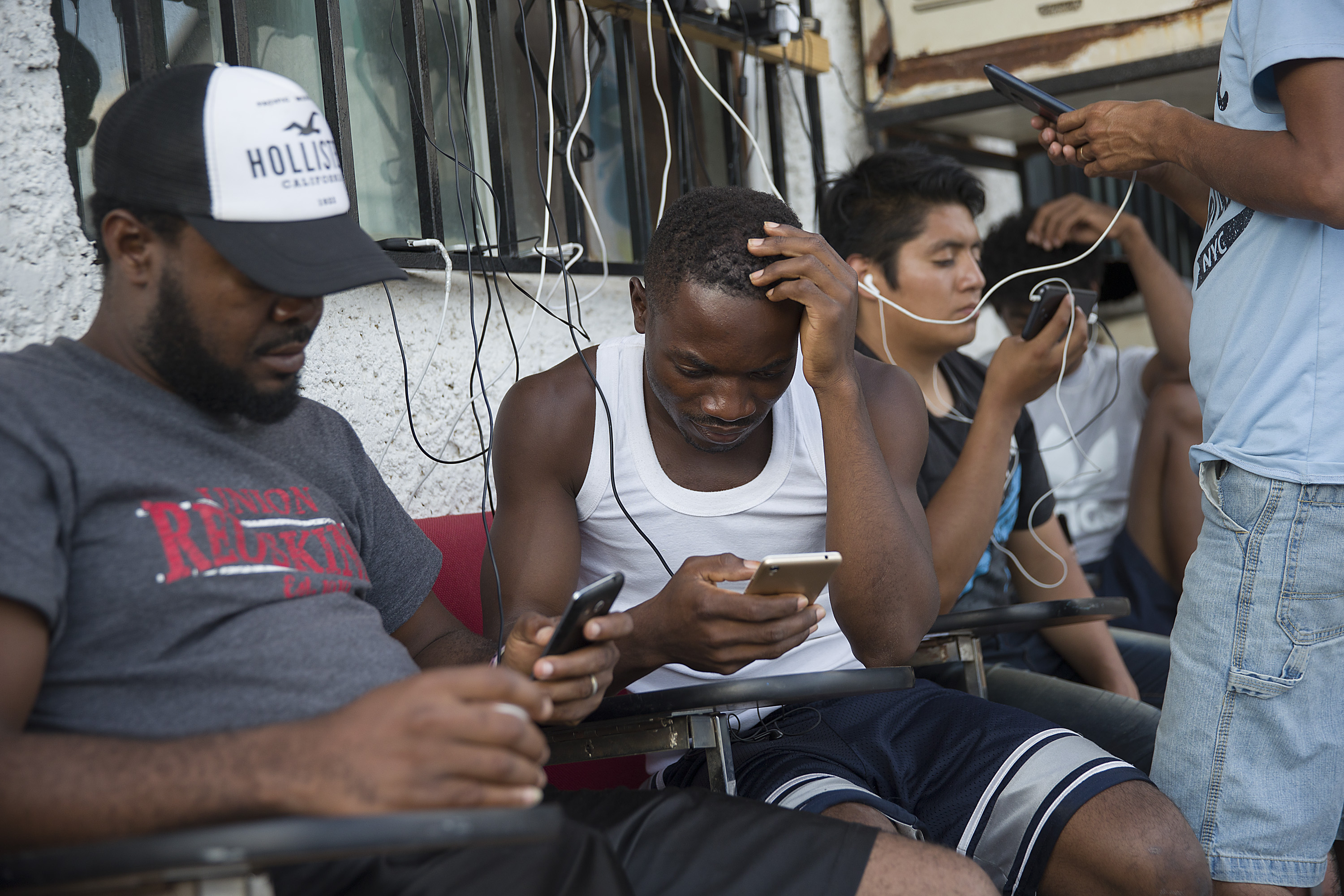 Migrants from Cameroon use their cell phones as they relax at the Albergue Para Migrantes El Buen Samaritano while waiting to have their number on a waiting list that is months long to be called to have an initial interview with a U.S. asylum officer on June 5, 2019, in Ciudad Juarez, Mexico. (Credit: Joe Raedle/Getty Images)