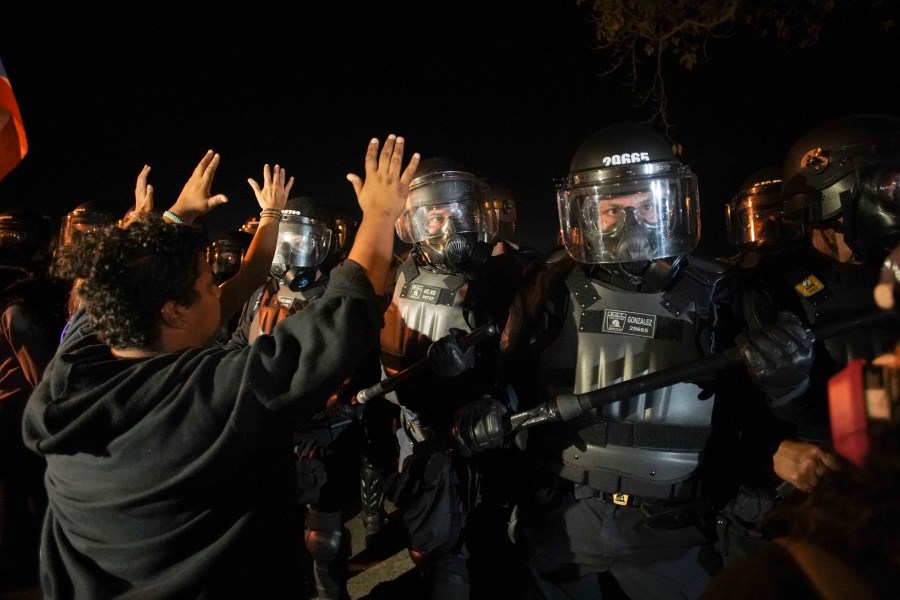 Protesters hold up their hands as they gather behind La Fortaleza to protest the newly designated governor, a member of the outgoing governor's New Progressive Party (PNP), as he was sworn in, in San Juan, Puerto Rico on Aug. 2, 2019. (Credit: ERIC ROJAS/AFP/Getty Images)