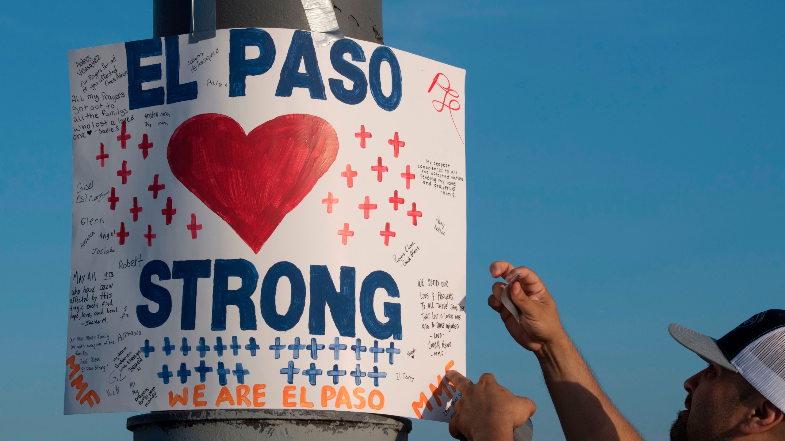 A man installs a 'El Paso Strong' sign at the makeshift memorial for victims of the shooting that left a total of 22 people dead at the Cielo Vista Mall Walmart in El Paso, Texas, on August 6, 2019. (Credit: MARK RALSTON/AFP/Getty Images)