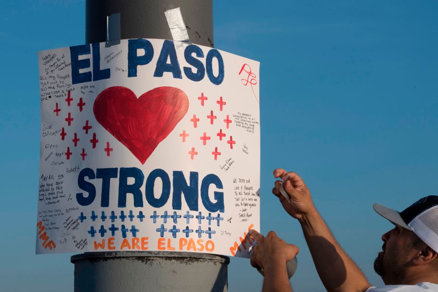 A man installs a 'El Paso Strong' sign at the makeshift memorial for victims of the shooting that left a total of 22 people dead at the Cielo Vista Mall Walmart in El Paso, Texas, on August 6, 2019. (Credit: MARK RALSTON/AFP/Getty Images)