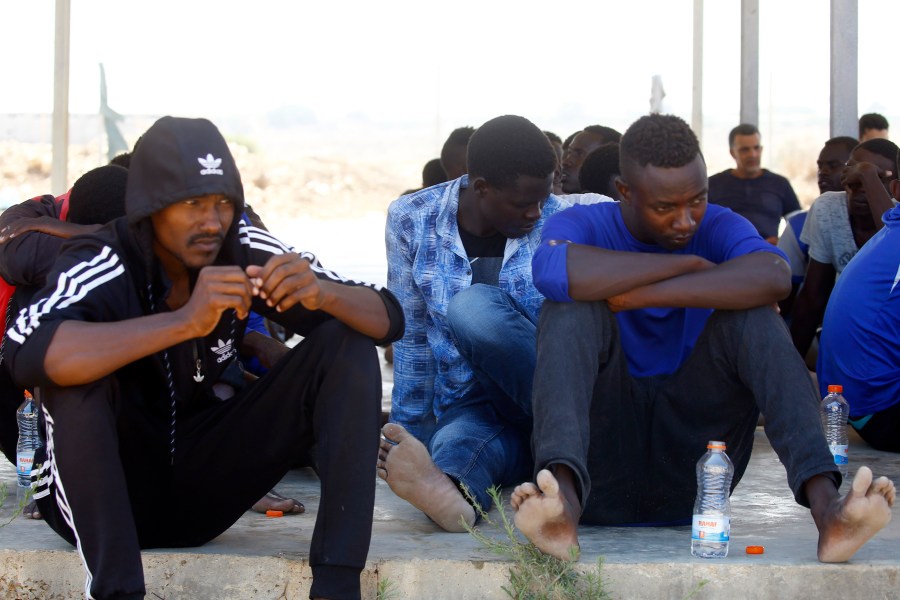 Rescued migrants sit in a coast guard point in Khoms, some 60 miles from the Libyan capital of Tripoli, on Aug. 27, 2019, after they were saved off the coast of the Libyan city. (Credit: MAHMUD TURKIA/AFP/Getty Images)