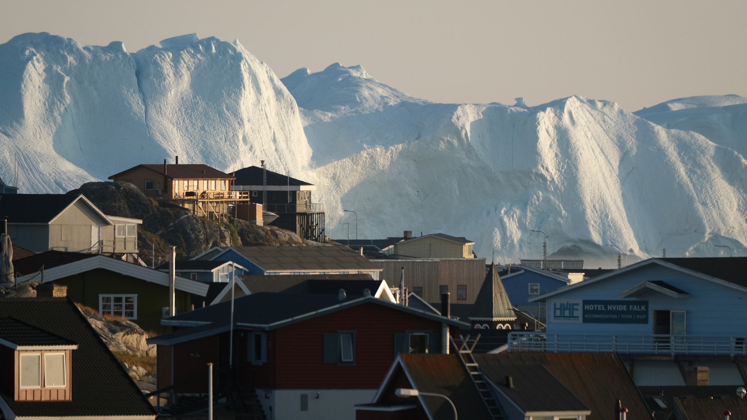 Icebergs in the Ilulissat Icefjord loom behind buildings on Aug. 4, 2019 in Ilulissat, Greenland. (Credit: Sean Gallup/Getty Images)