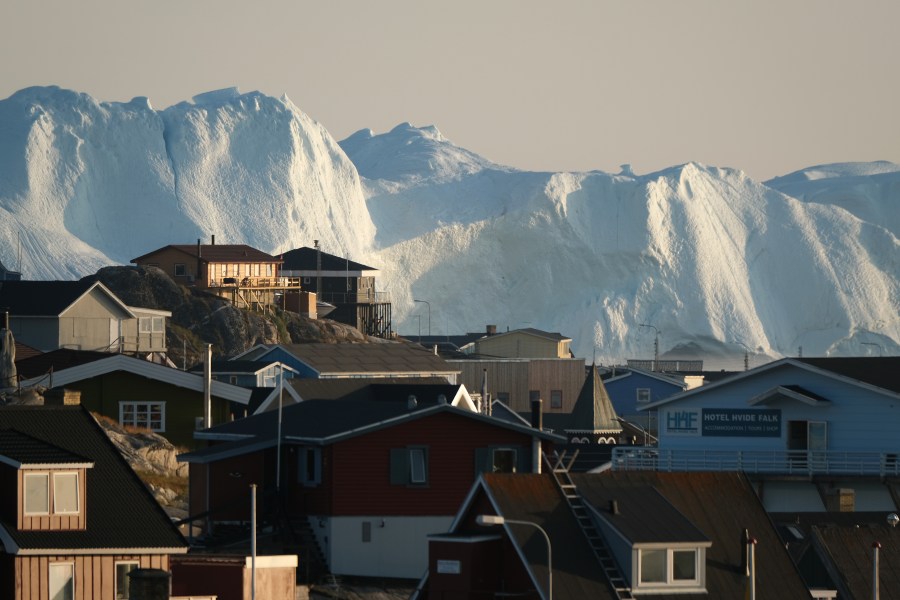 Icebergs in the Ilulissat Icefjord loom behind buildings on Aug. 4, 2019 in Ilulissat, Greenland. (Credit: Sean Gallup/Getty Images)