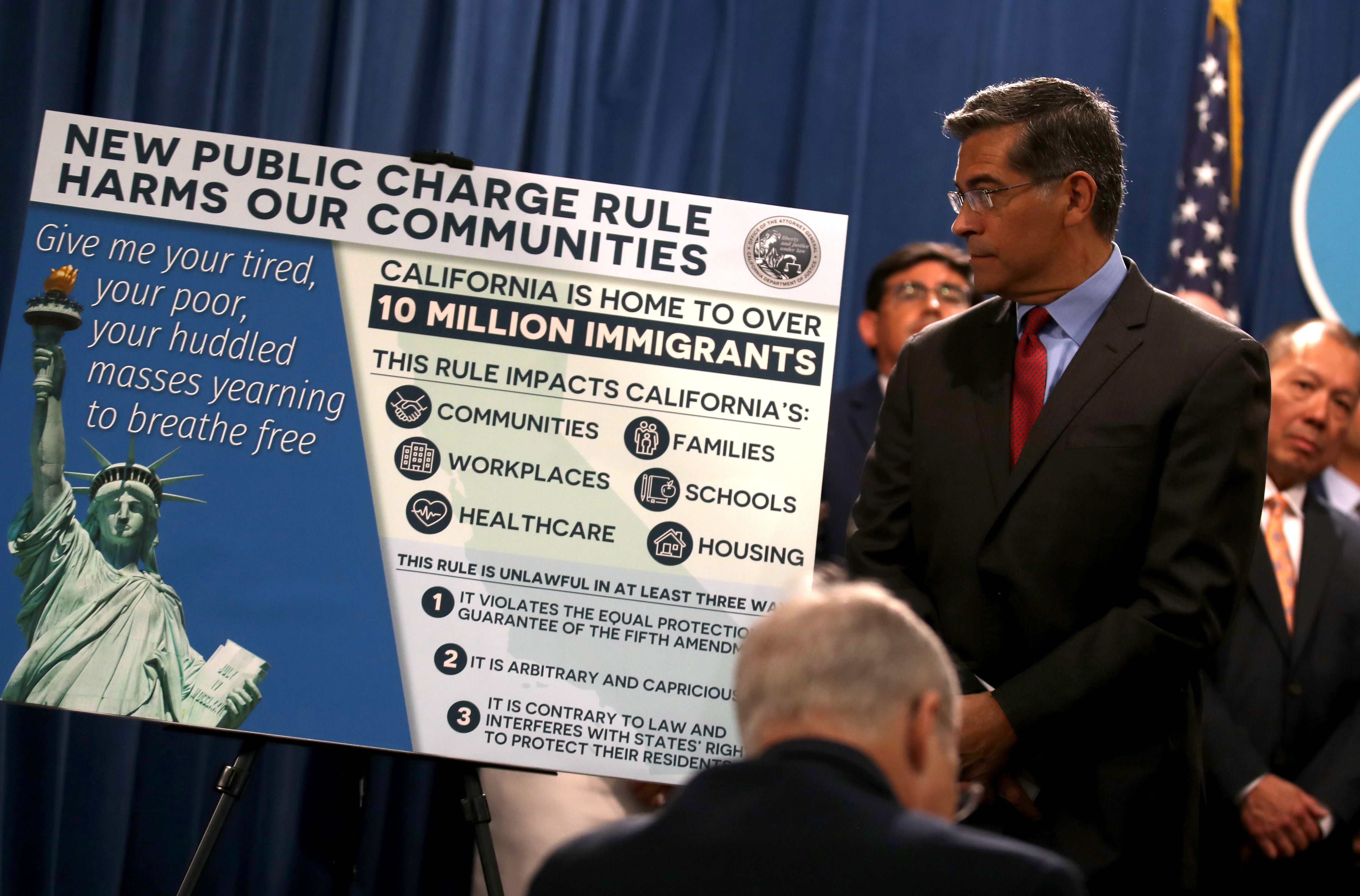 California Attorney General Xavier Becerra looks at a poster displayed during a news conference with Gov. Gavin Newsom at the State Capitol on Aug. 16, 2019 in Sacramento. (Credit: Justin Sullivan/Getty Images)