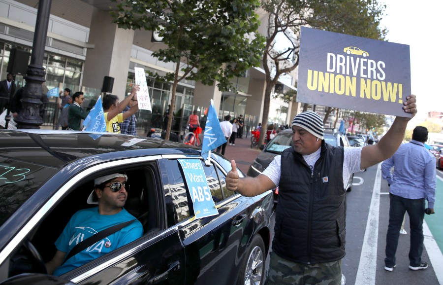 Ride-hailing app drivers hold signs during a protest outside of Uber headquarters in San Francisco on Aug. 27, 2019. (Credit: Justin Sullivan / Getty Images)