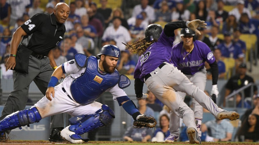 Russell Martin #55 of the Los Angeles Dodgers tags Raimel Tapia #15 of the Colorado Rockies out at the plate on a single by Sam Hilliard #43 as umpire Greg Gibson #53 makes the call in the eighth inning at Dodger Stadium on September 21, 2019 in Los Angeles, California. (Credit: John McCoy/Getty Images)